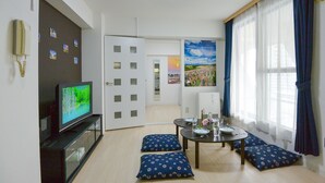 A living room with a TV, a dining table with chairs, and a kitchen in the background. - KIYAZA City Sapporo (Sapporo)