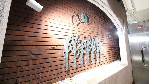 A brick wall with a metal tree sculpture and a stainless steel refrigerator. - KIYAZA City Sapporo (Sapporo)