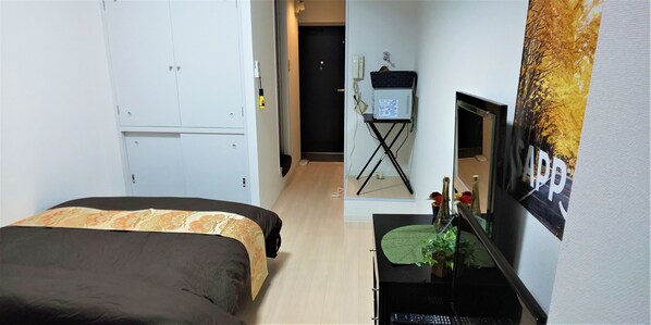 A bedroom with a bed, a desk with a computer, a small table with a plant, and a poster on the wall. - KIYAZA City Sapporo (Sapporo)