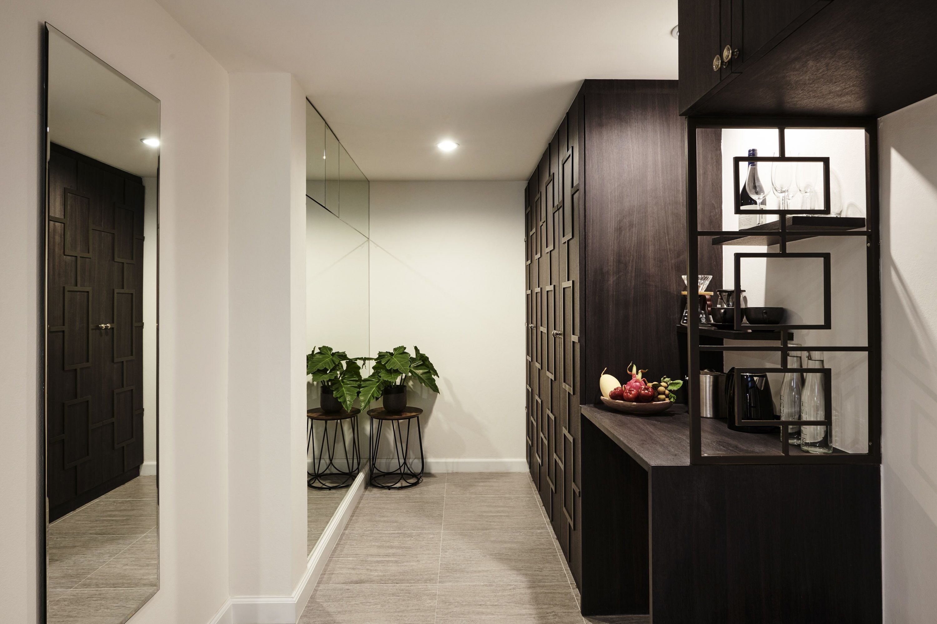 A modern hallway with a dark wooden cabinet, a mirror, and a potted plant.