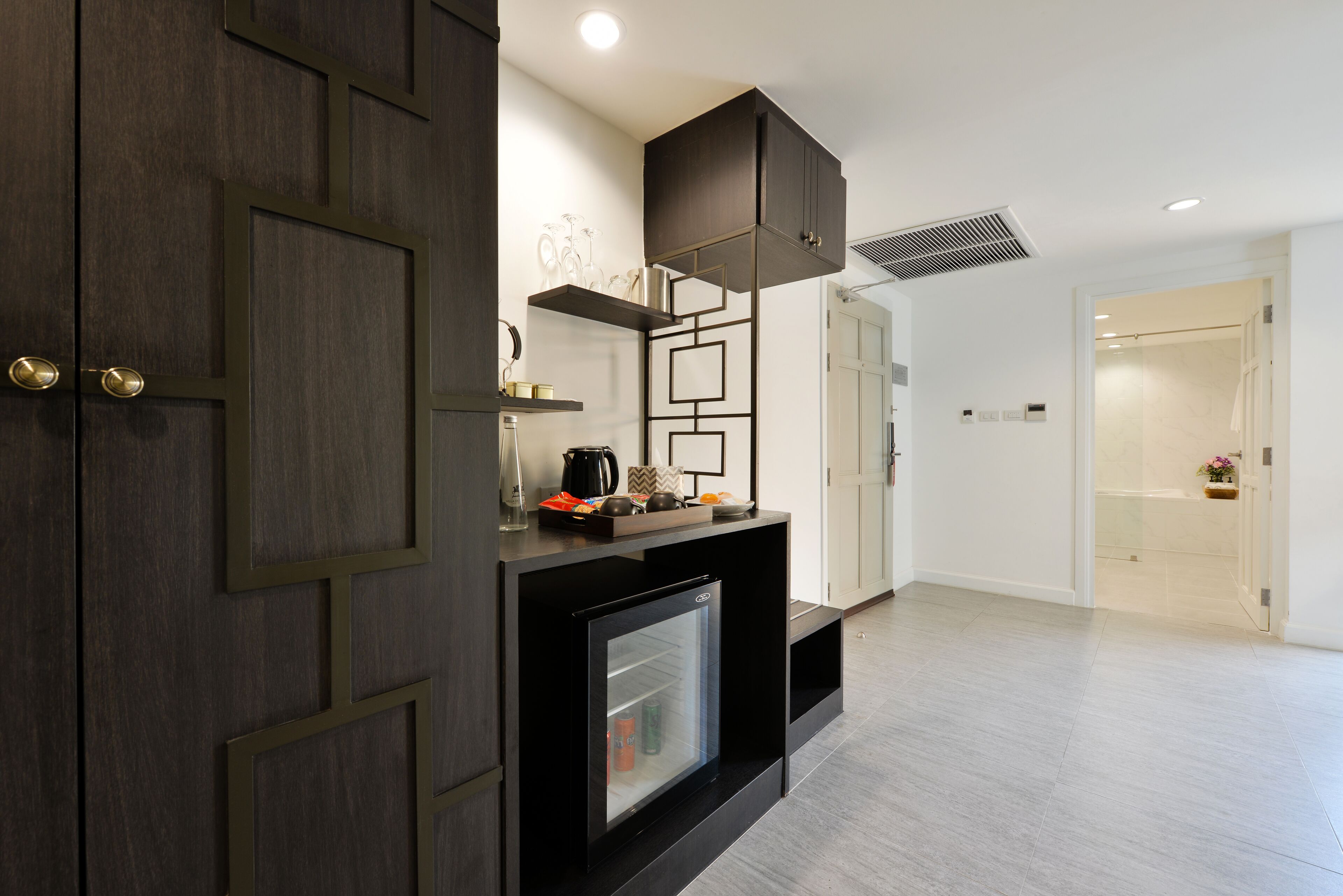 A modern kitchen with dark cabinetry, a built-in refrigerator, and a countertop with various items.