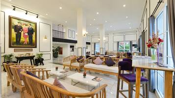 A spacious hotel lobby with wooden furniture, a large painting, and a view of the outdoors.