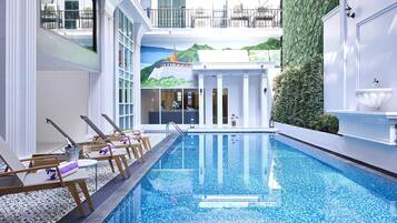 A pool area with lounge chairs, a clear pool, and a mural of a mountain landscape.
