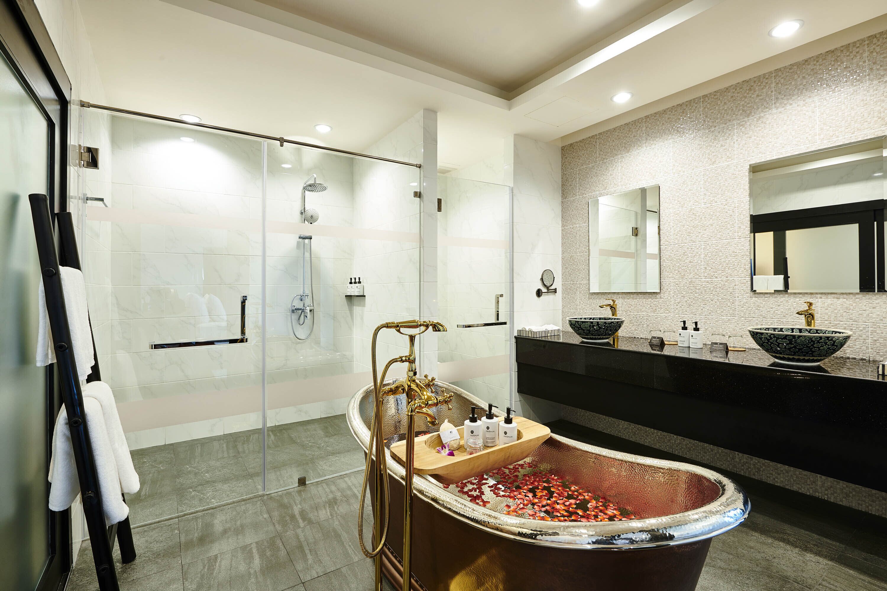 A modern bathroom with a glass-enclosed shower, a freestanding bathtub, and a vanity with a large mirror.