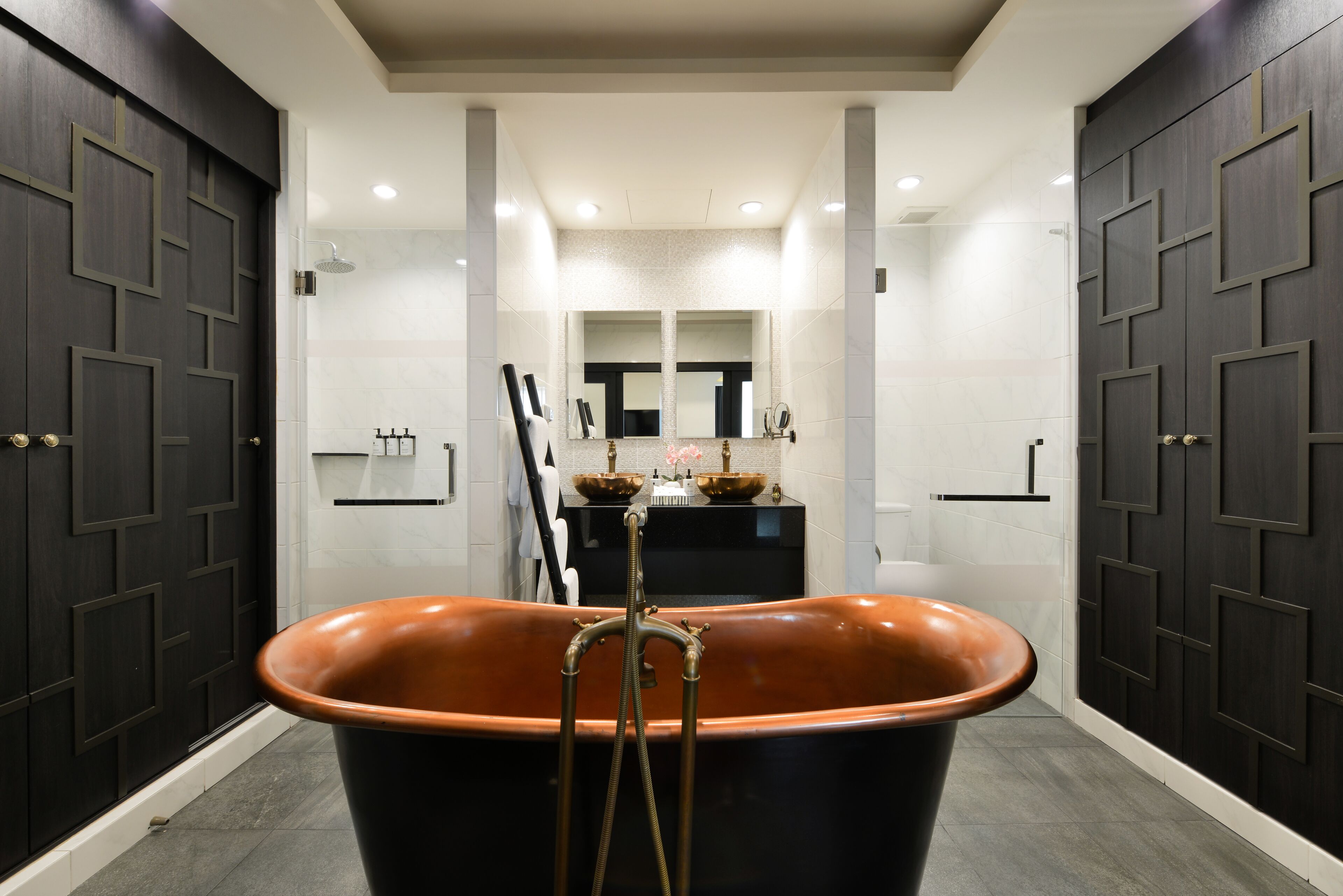 A modern bathroom with a freestanding bathtub, a large mirror, and a vanity with a sink and towel rack.