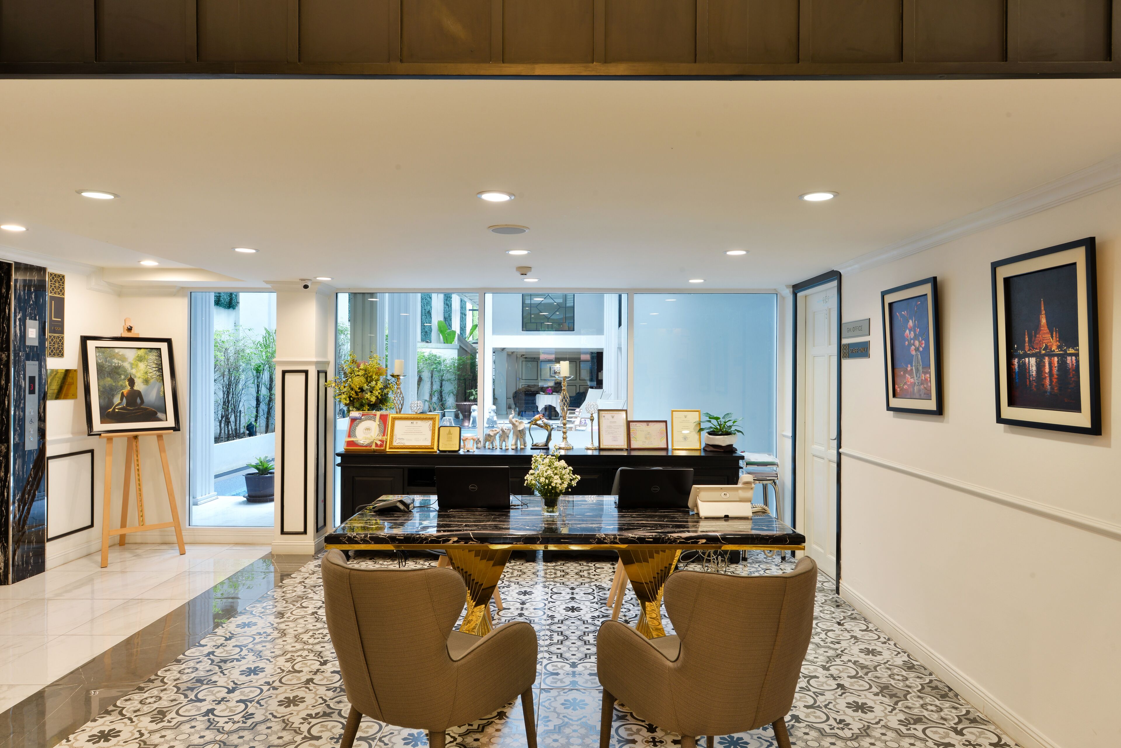 A modern dining area with a marble table, two chairs, and framed artwork on the walls.