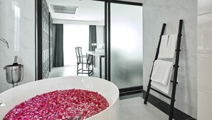 Un baño moderno con una bañera grande llena de pétalos de rosa, un perchero y una zona de ducha.