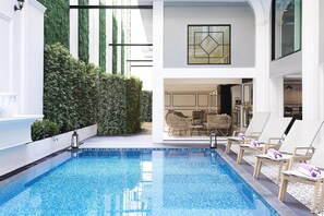 A modern indoor pool area with a clear view of a dining area in the background. - Villa de Pranakorn (Bangkok)