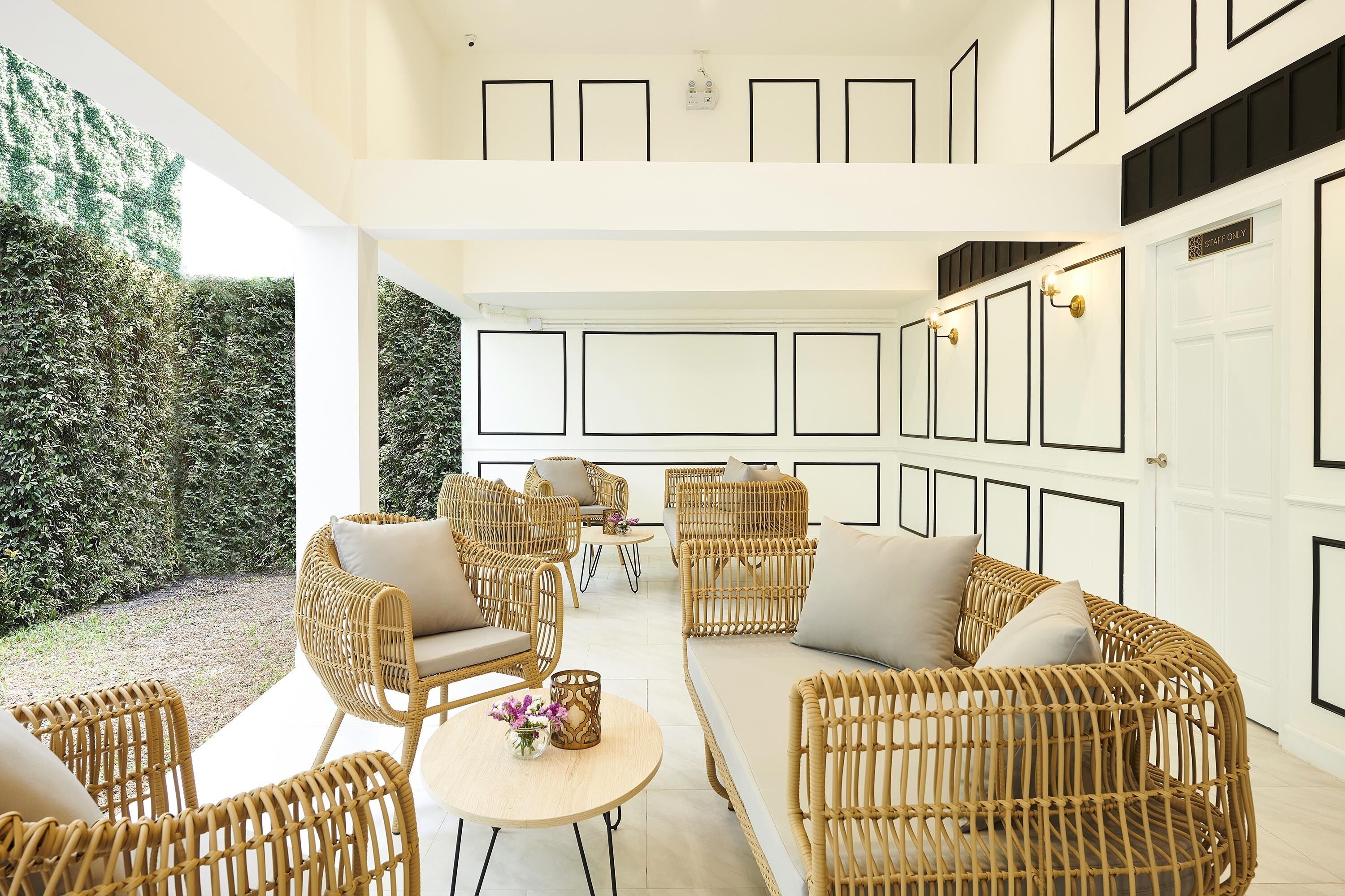 A spacious outdoor seating area with wicker furniture and a view of a well-maintained garden.