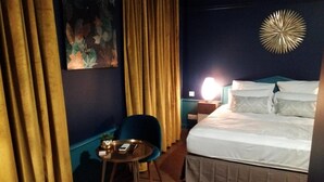 Habitación de hotel con cama, mesita de noche, una silla y un adorno en la pared.