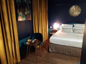 A hotel room with a bed, a chair, a table, and a nightstand with a lamp. - Logis Hotel le Cedre de Soyons (Soyons)
