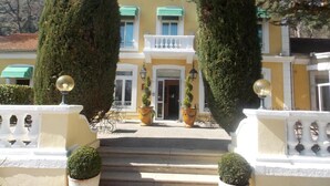 Un edificio con fachada amarilla, balcones blancos y una entrada central con escalones.