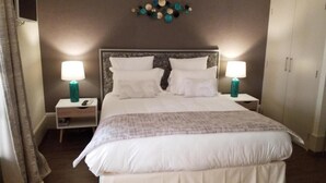 A neatly made bed with white linens and a gray blanket, flanked by two bedside tables with teal lamps, a wall-mounted decorative piece, and a wardrobe. - Logis Hotel le Cedre de Soyons (Soyons)