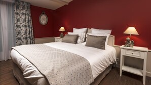 Habitación de hotel con una cama grande, dos mesitas de noche, una lámpara de noche, un reloj de pared y una ventana con cortinas.