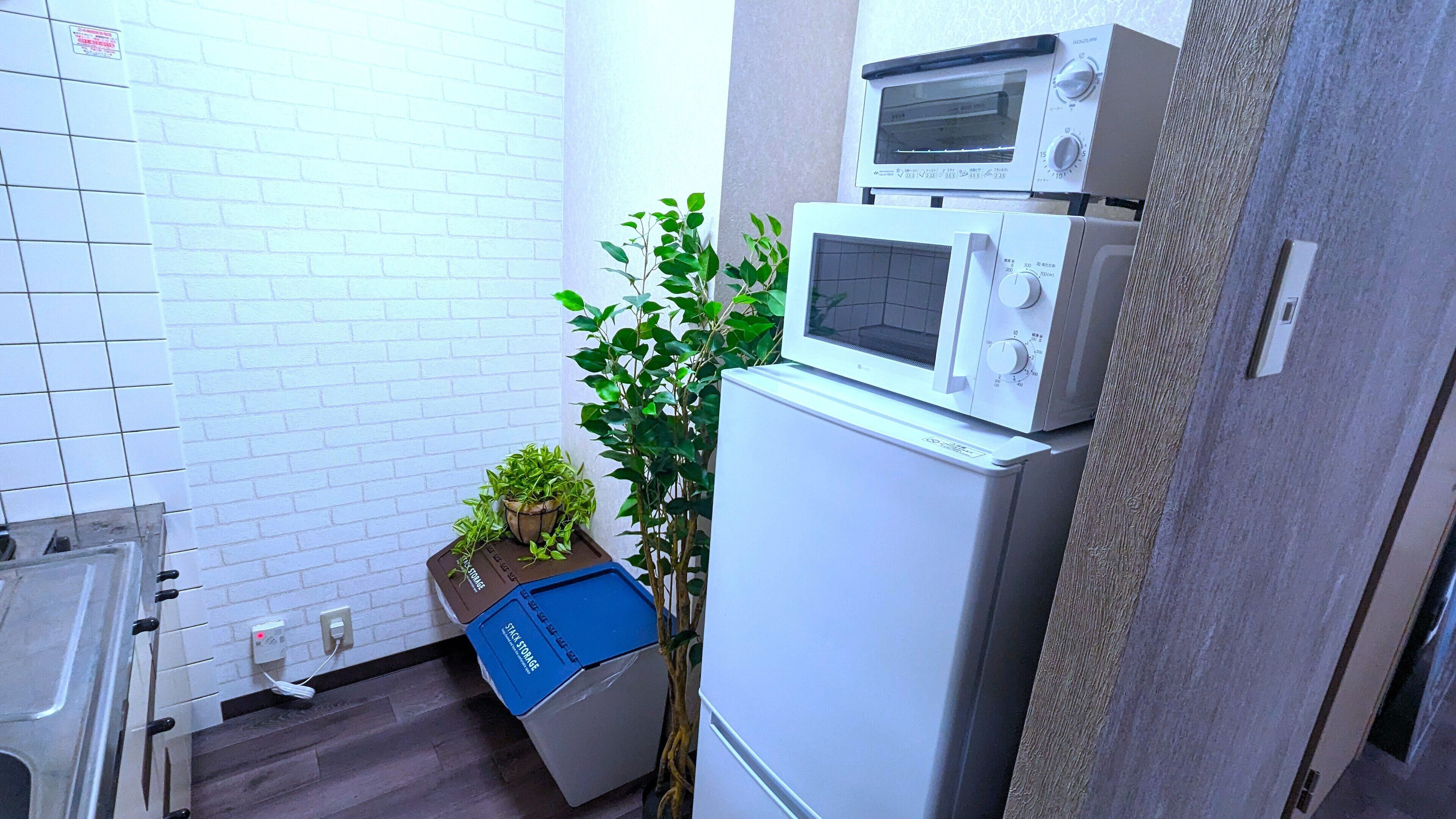 Una cucina compatta con forno a microonde, un piccolo frigorifero e una pianta in vaso.