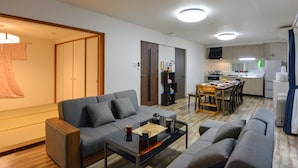 Una sala moderna con un sofá, una mesa de centro y un comedor con sillas, y una cocina al fondo.