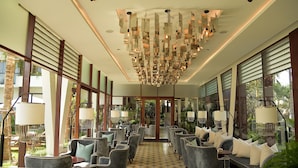 Een ruime lobby met een moderne kroonluchter, comfortabele zitplaatsen en grote ramen met uitzicht op de omgeving.