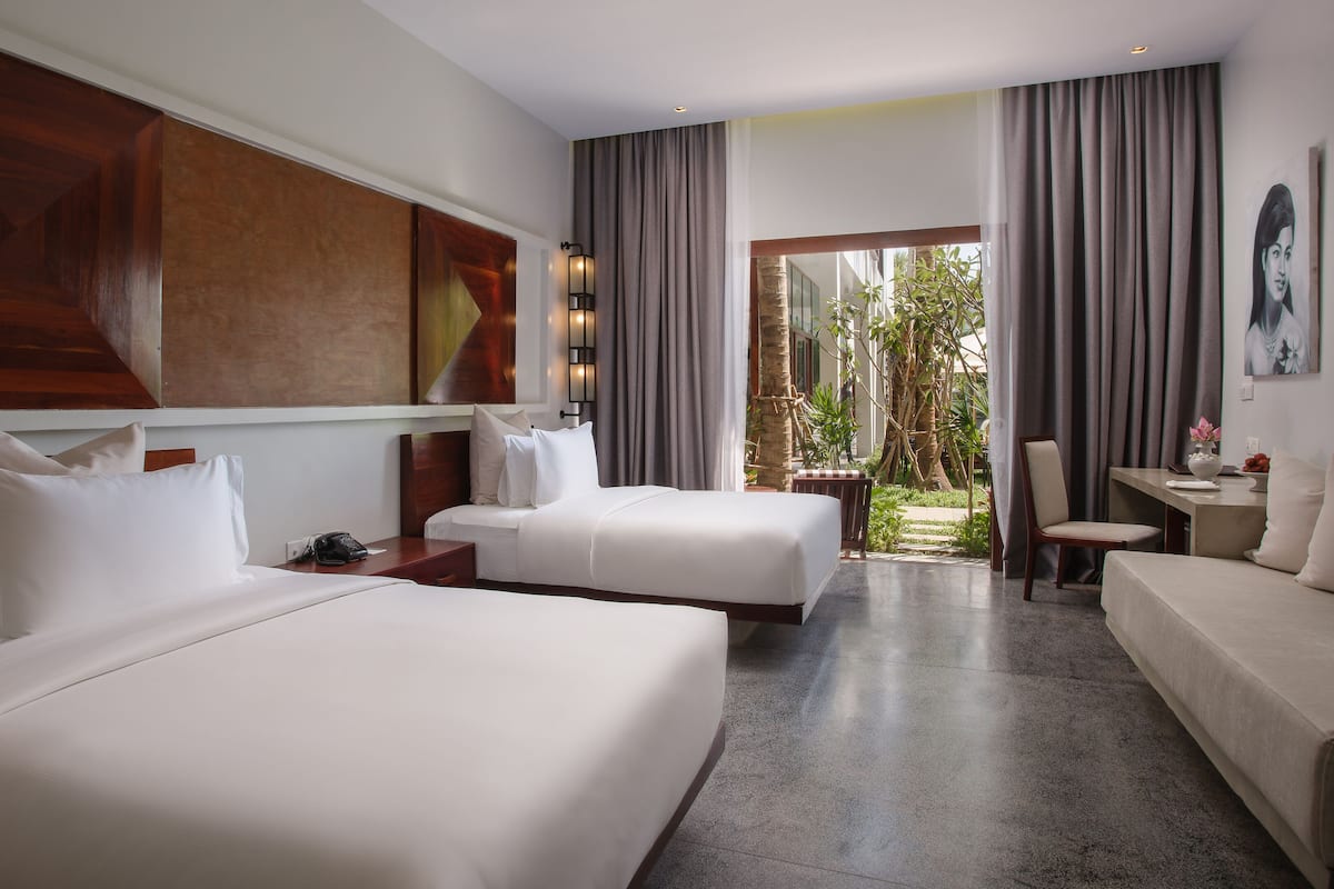 Une chambre d’hôtel avec deux lits, un bureau et une vue sur l’extérieur.