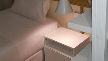 Un dormitorio con cama, mesita de noche y lámpara colgante.