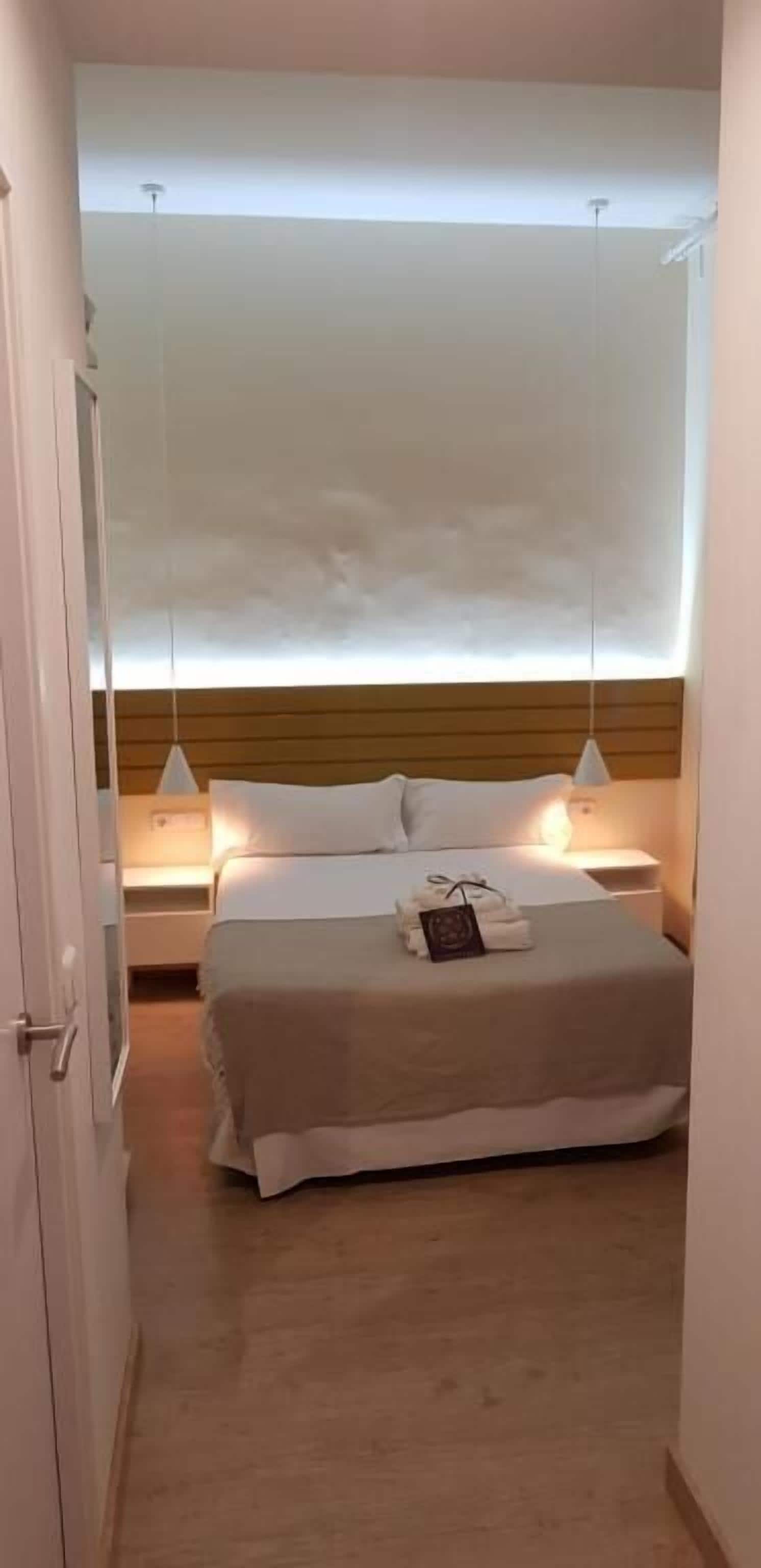 A bedroom with a bed, bedside lamps, and a wooden headboard.