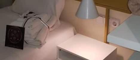 Une chambre à coucher avec un lit, une table de chevet et une lampe suspendue.