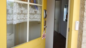 A yellow door with a frosted glass window, a doormat, a doorbell, and a no-smoking sign. - Cozy vacation home in Julianadorp Strandslag (Julianadorp)