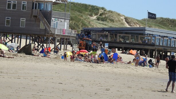 A beachside building with a wooden deck and a flag. - Cozy vacation home in Julianadorp Strandslag (Julianadorp)