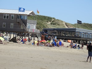 Ein Gebäude am Strand mit einer Holzterrasse und einer Flagge.