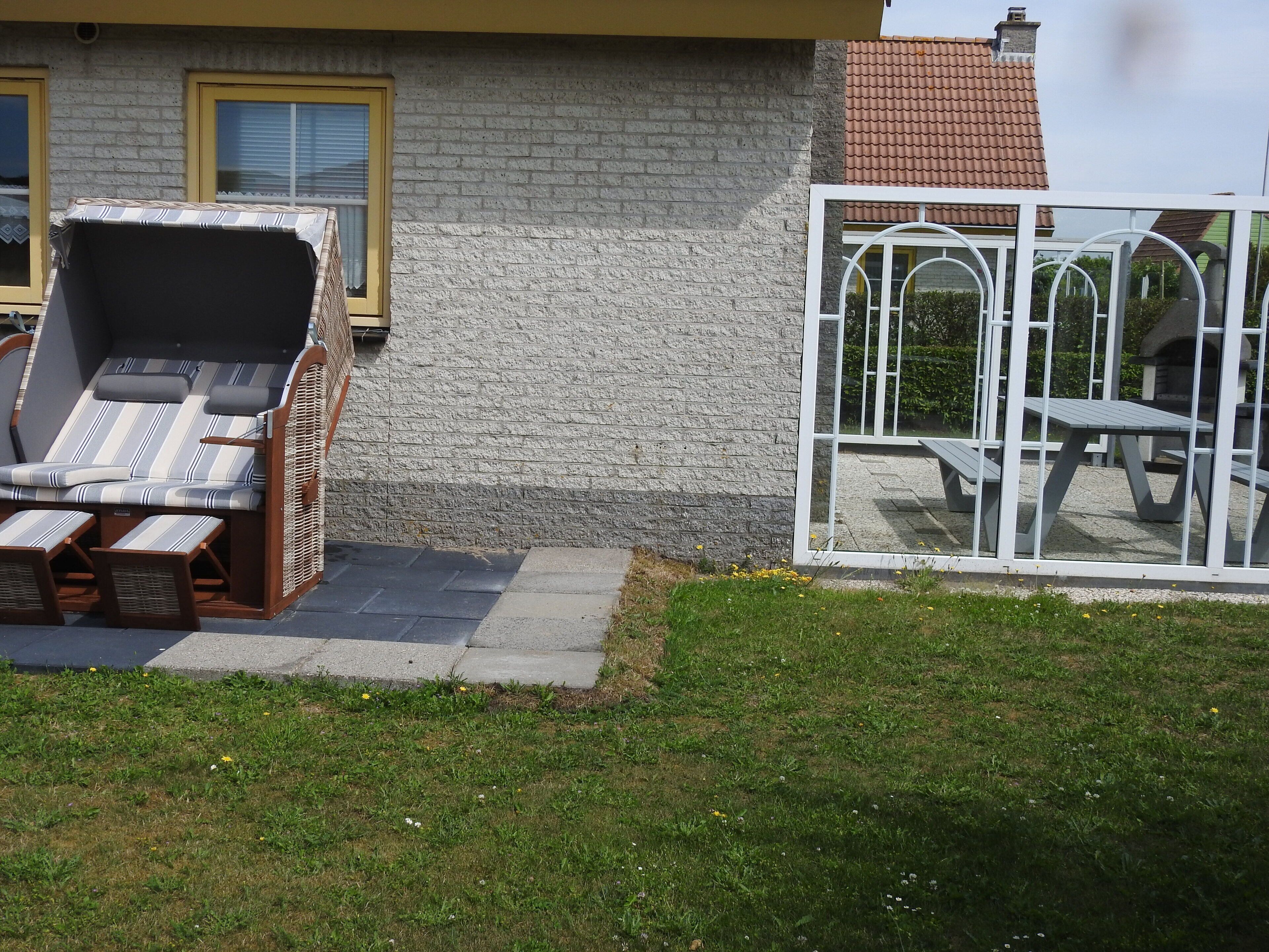 A patio area with a sun lounger and a white metal table and chair set.