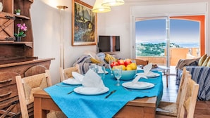 A dining area with a blue tablecloth, wooden chairs, and a view of the city through a large window. - Stunning  villa for 6 people with WIFI, TV, patio, pets allowed and panoramic view (Begur)