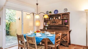 A dining area with a blue tablecloth, wooden chairs, and a wooden cabinet with decorative plates. - Stunning  villa for 6 people with WIFI, TV, patio, pets allowed and panoramic view (Begur)