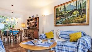A living room with a sofa, a dining table, and a painting of a bridge. - Stunning  villa for 6 people with WIFI, TV, patio, pets allowed and panoramic view (Begur)