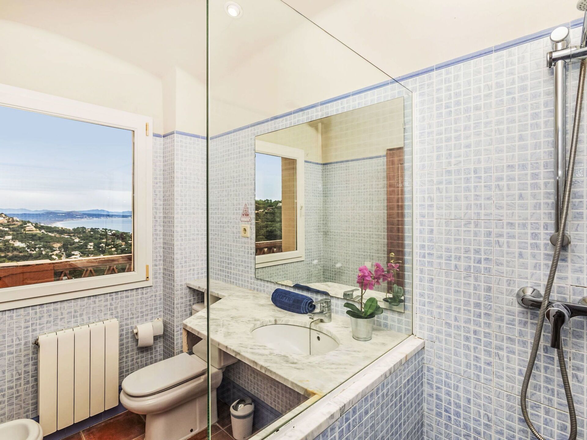 Une salle de bain avec vue sur le paysage, des toilettes, un lavabo avec un miroir et une douche.