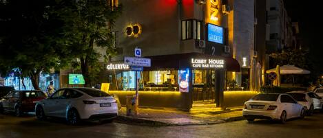 A hotel with a visible entrance, a sign for a lobby house cafe bar kitchen, and parked cars.