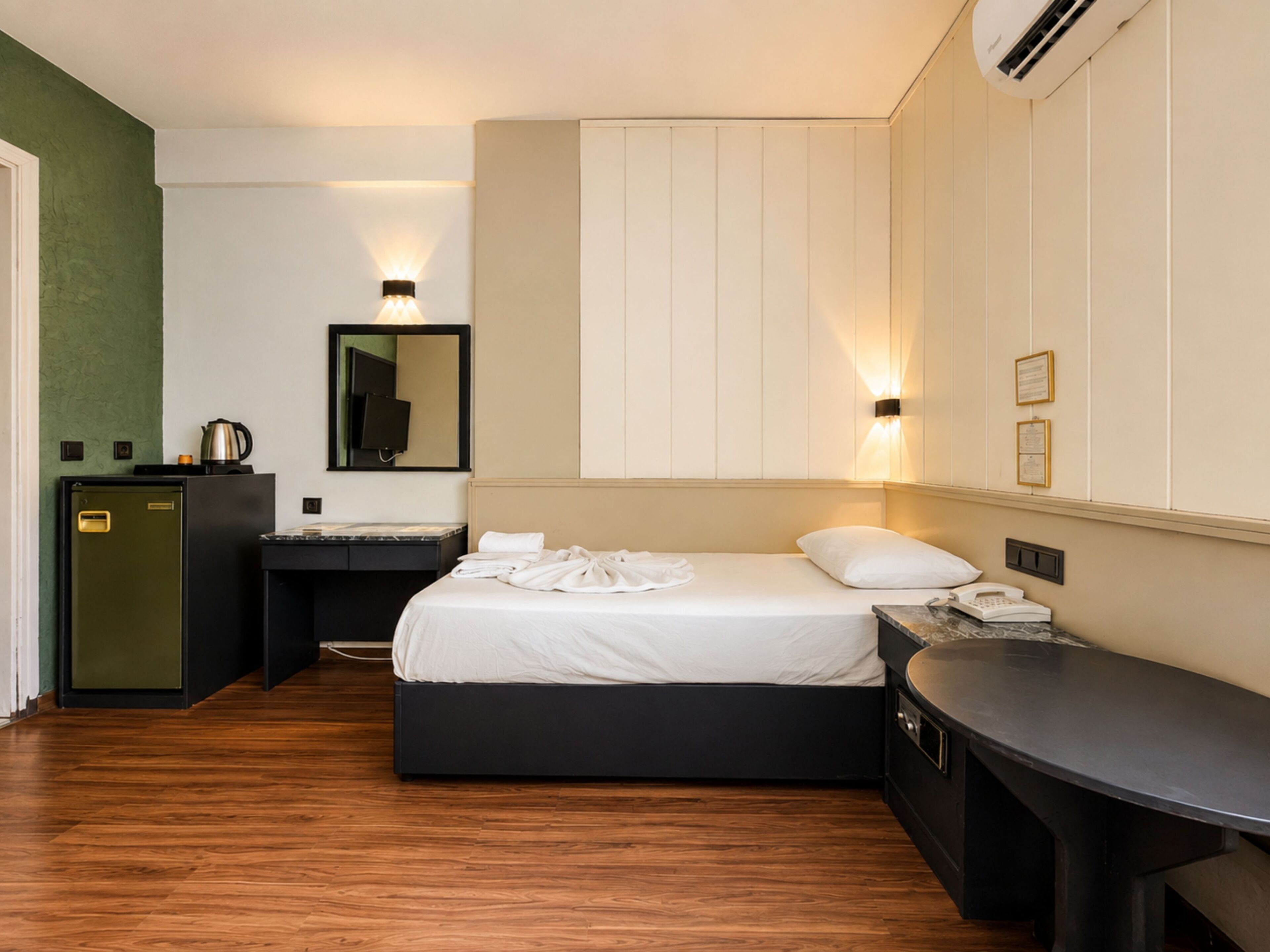 Ein Hotelzimmer mit Bett, Nachttisch, Schreibtisch und einer kleinen Küchenzeile.