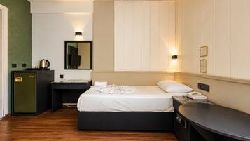Ein Hotelzimmer mit Bett, Nachttisch, Schreibtisch und einer kleinen Küchenzeile.