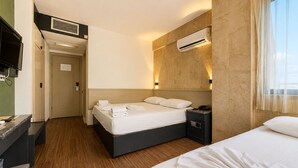Habitación de hotel con cama, mesitas de noche, televisión, aire acondicionado y vistas al exterior.