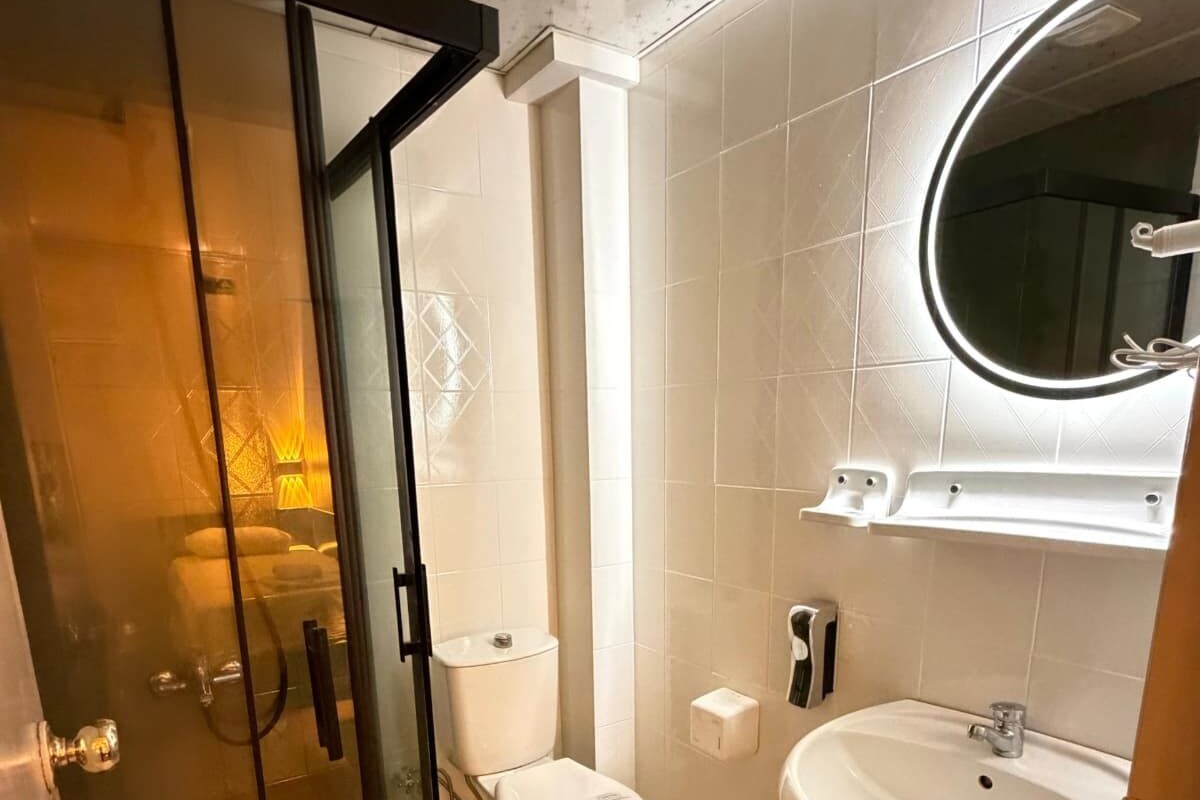 A modern bathroom with a glass-enclosed shower, a toilet, and a sink with a mirror above it.