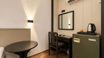 A compact hotel room with a desk, chair, and a small kitchenette.