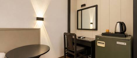 Una habitación de hotel pequeña con escritorio, silla y kitchenette.