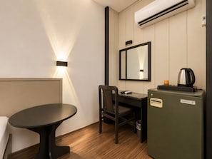 Una habitación de hotel pequeña con escritorio, silla y kitchenette.