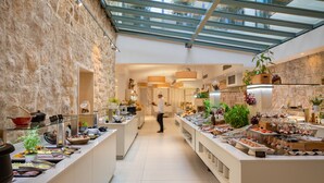 A modern hotel lobby with a glass ceiling, stone walls, and a buffet area with various food options. - Bluesun Mala Berulia (Brela)