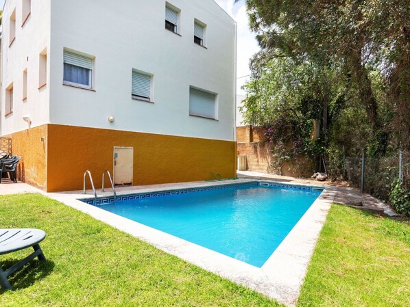 A swimming pool adjacent to a building with a white and orange facade, a door, and windows. - Beautiful private villa for 8 guests with WIFI, private pool, TV, patio and pets allowed (Calonge)