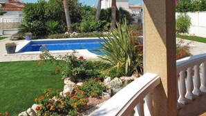 A pool surrounded by a garden with various plants and flowers.