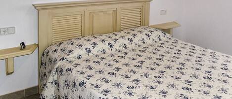 Un dormitorio con cama, cabecero de madera, mesita de noche y un reloj en la pared.