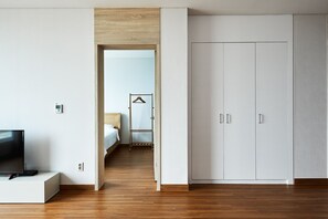 Una habitación de hotel moderna con suelo de madera, una cama, un armario y un televisor sobre un mueble.