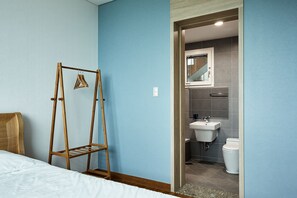 Un dormitorio con una escalera de madera, una cama y un baño con lavamanos e inodoro.