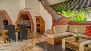 A modern living room with a sofa, coffee table, and dining area with chairs and a kitchen in the background. - 2 BR Villa in Seminyak, 25sqm Private Pool, 5 mnts walk to shopping area for 6 (Seminyak)
