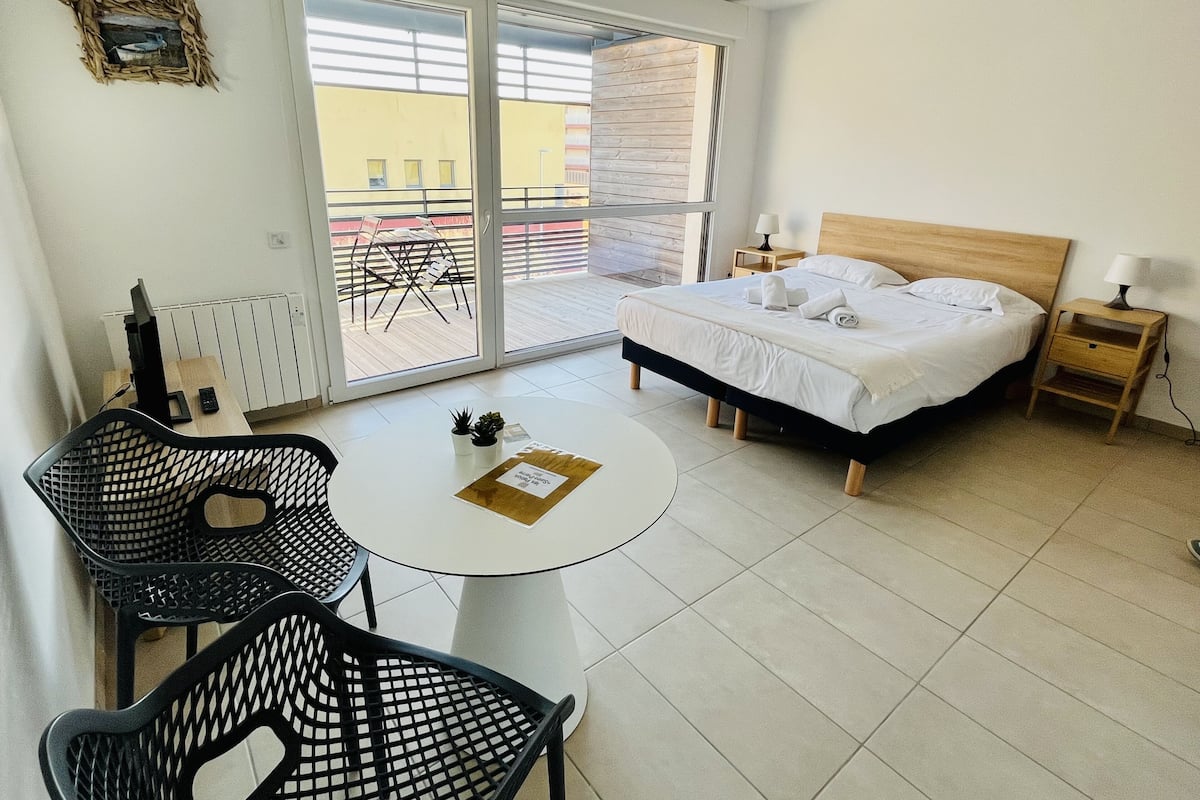 A modern bedroom with a bed, a small table, and a chair.