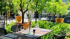 An outdoor dining area with tables and chairs, surrounded by greenery and potted plants. - Les Patios de Saint-Pierre (Palavas-les-Flots)